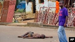 The lifeless body of a man lays unattended in the street as locals suspect him of dying from the deadly Ebola virus, as government warns the public not to leave Ebola victims in the streets in the city of Monrovia, Liberia, Tuesday, Aug. 5, 2014. A seco