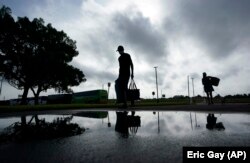 People looking to evacuate the path of Hurricane Laura arrive at the civic center where evacuation buses wait, Wednesday, Aug. 26, 2020, in Port Arthur, Texas.