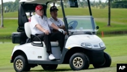 FILE - Former President Donald Trump rides in a golf cart at Trump National Doral Golf Club, in Doral, Florida. Oct. 27, 2022. Today's shooting incident took place at another golf club he owns in the state, Trump International Golf Club in West Palm Beach.