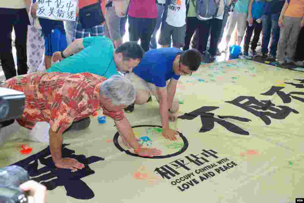 佔中三位發起人在印有「和平抗爭、不屈不撓」的橫額上打手印，表達和平抗爭的決心（美國之音湯惠芸拍攝）