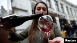 FILE - A shop assistant pours wine during a wine festival in Tbilisi, Georgia, Oct. 15, 2017.