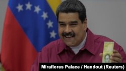 Venezuela's President Nicolas Maduro holds a 100,000 bolivar note as he speaks during a meeting with ministers in Caracas, Venezuela, Nov. 1, 2017. 