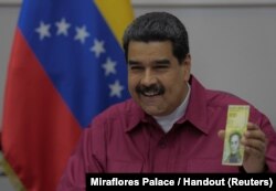 Venezuela's President Nicolas Maduro holds a 100,000 bolivar note as he speaks during a meeting with ministers in Caracas, Venezuela, Nov. 1, 2017.