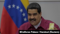 Presiden Venezuela Nicolas Maduro memegang uang kertas 100.000 bolivar ketika berbicara dalam sebuah pertemuan dengan para menteri di Caracas, Venezuela, 1 November 2017. 