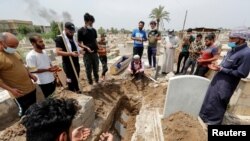 Mourners pray during the burial of a man, who was killed in a fire at a hospital that had been equipped to house coronavirus disease (COVID-19) patients, at a cemetery in Baghdad, Iraq, Apr. 25, 2021. 
