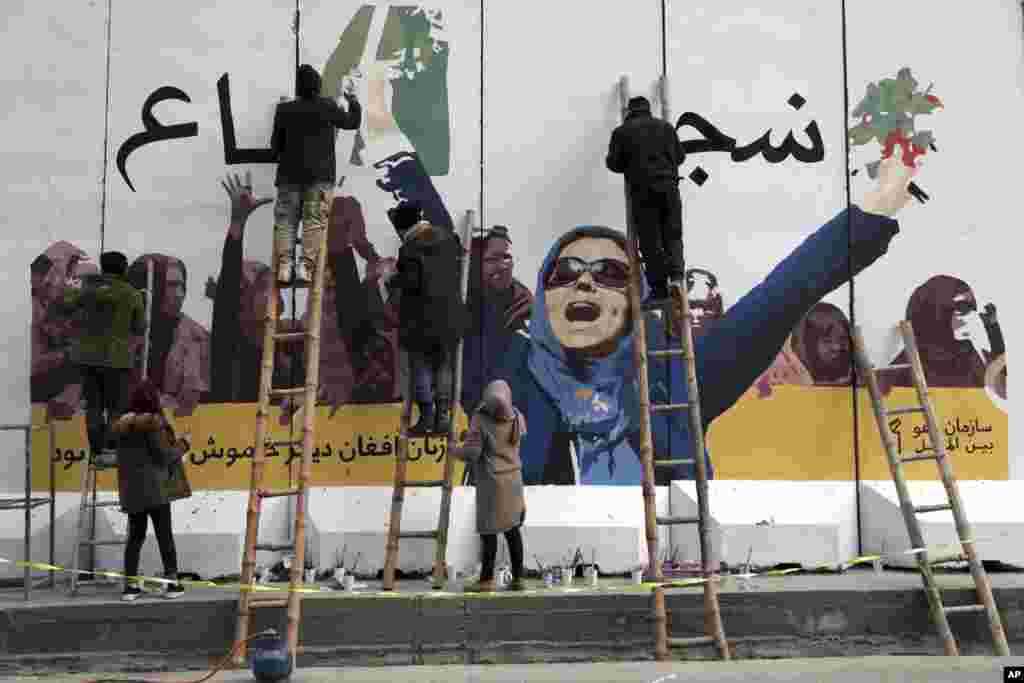 Independent Afghan artists draw a graffiti on a barrier wall of the Ministry of Women&#39;s Affairs to mark International Women&#39;s Day in Kabul, March 8, 2019.