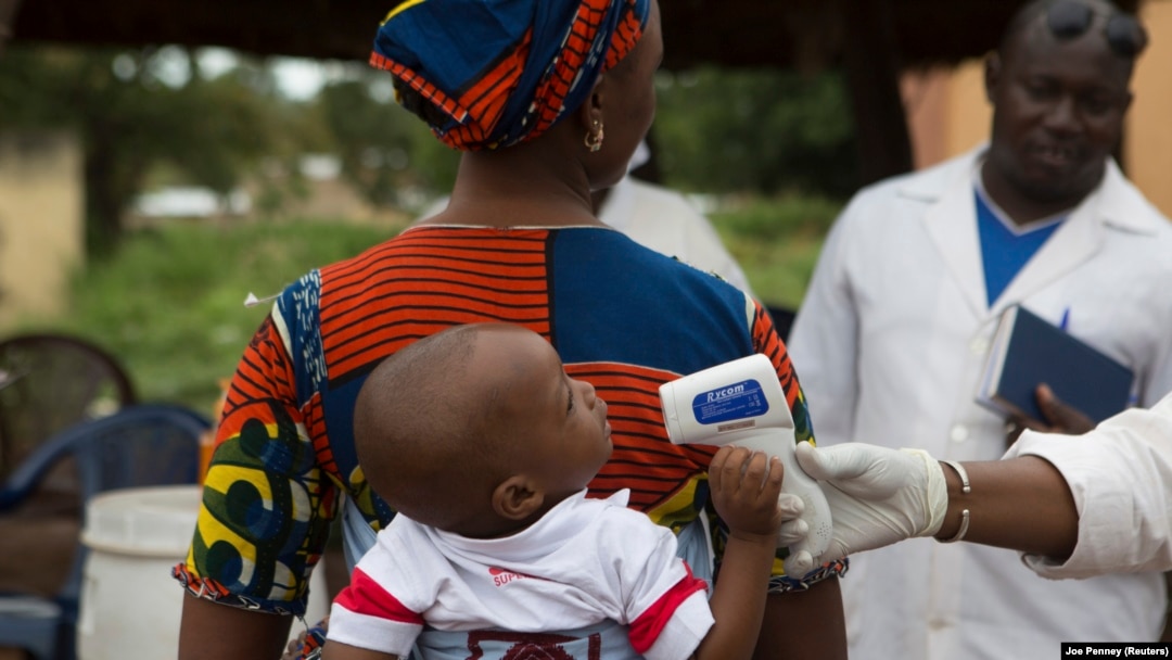 Seorang petugas kesehatan memeriksa suhu bayi yang memasuki Mali dari Guinea di perbatasan di Kouremale, 2 Oktober 2014. Seorang perempuan Mali melahirkan sembilan bayi pada 4 Mei 2021.(Foto: REUTERS/Joe Penney)