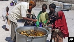 Somali children from southern Somalia, receive cooked food in Mogadishu, Somalia, Monday, Aug 15, 2011