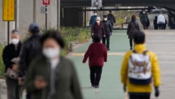 People wearing face masks to help curb the spread of the coronavirus walk along a stream during a lunch break in Seoul, South Korea on Dec. 9, 2021.