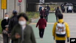 People wearing face masks to help curb the spread of the coronavirus walk along a stream during a lunch break in Seoul, South Korea on Dec. 9, 2021.