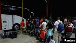 Migrantes hacen fila para abordar un autobús con destino a Huixtla y continuar con sus trámites para obtener un formulario de migración que les permitirá transitar por México y llegar a la frontera norte, en Mapastepec, México, el 2 de enero de 2024.