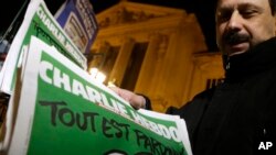 Penjual koran memasang tabloid Charlie Hebdo di kiosnya di Nice, Perancis Selatan (14/1). (AP/Lionel Cironneau)