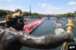 A photo taken from the bridge Alexandre III shows an athletics track installed on the river Seine with a tour boat passing by during a bid to promote the candidacy of the city of Paris for the 2024 Summer Olympics Games, June 23, 2017.