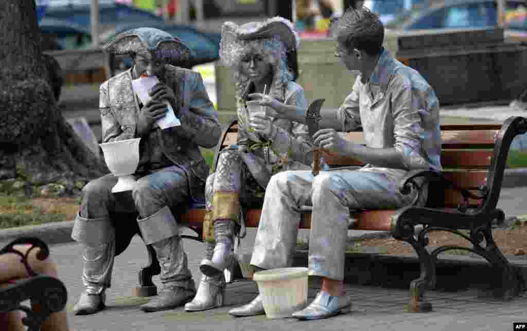 Street artists have a snack as they rest on a bench in the center of the Ukrainian capital Kiev. 