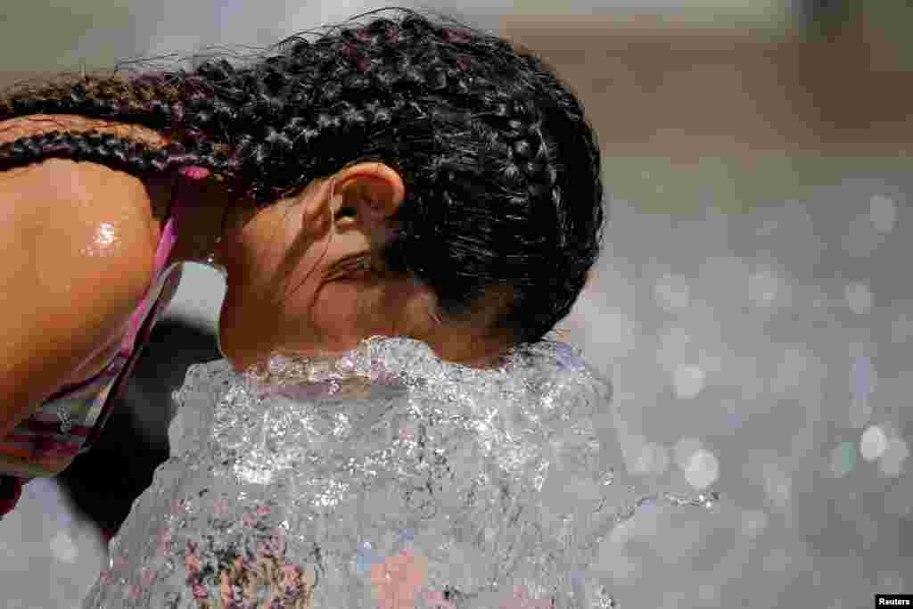 A child cools off in a fountain as a summer heatwave with high temperatures continues in Paris, France.