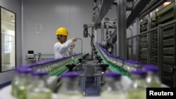 FILE - An employee works on a production line manufacturing drugs at the Yangtze River Pharmaceutical Group in Taizhou, Jiangsu province, China, Sept. 3, 2019.