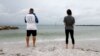 Dos personas pescan durante un clima nublado en la playa de Saint Pete, Florida, el domingo 4 de agosto de 2024.