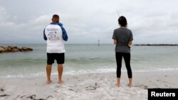 Dos personas pescan durante un clima nublado en la playa de Saint Pete, Florida, el domingo 4 de agosto de 2024.