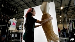 FILE - Samantha Estes prepares garments to be photographed at the ThredUp sorting facility in Phoenix, March 12, 2019. J.C. Penney and Macy’s are in the midst of rolling out a few dozen ThredUp branded shops each in time for the back-to-school season. 