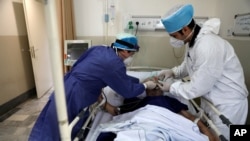 In this June 16, 2020, photo, medics tend to a COVID-19 patient at the Shohadaye Tajrish Hospital in Tehran, Iran, as it saw its highest single-day spike in reported cases.