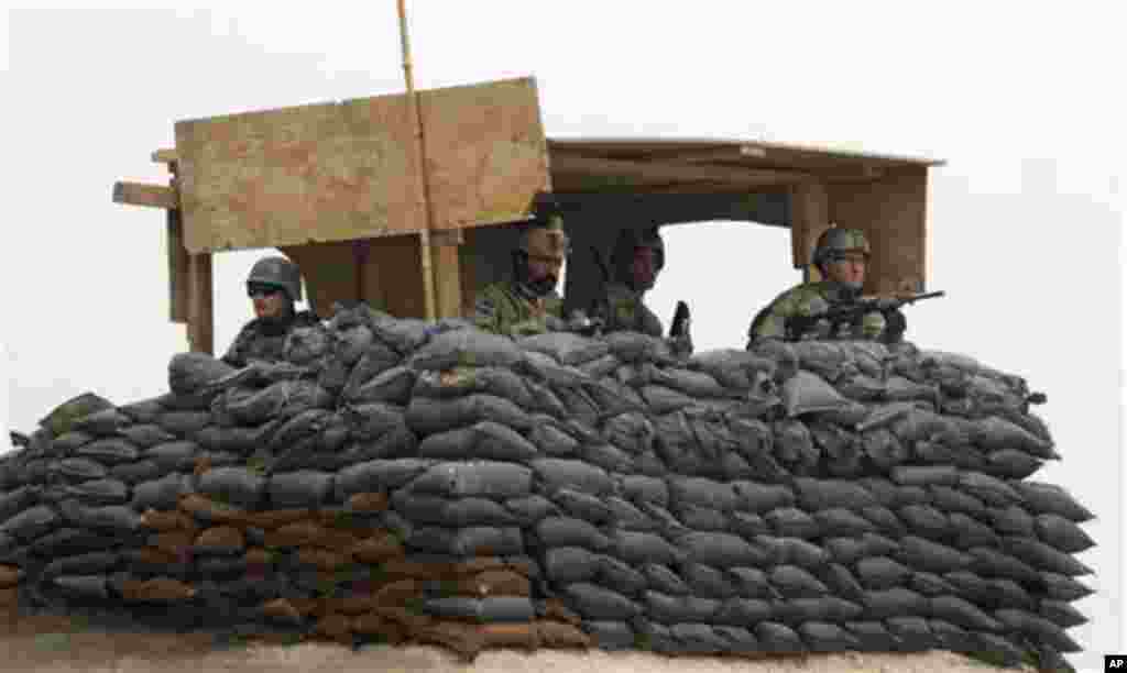 U.S. Army and Afghan soldiers are seen in a guard tower at their base in Panjwai, Kandahar province south of Kabul, Afghanistan, Sunday, March 11, 2012. Afghan President Hamid Karzai says a U.S. service member has killed more than a dozen people in a shoo