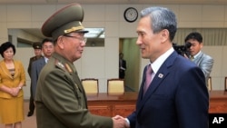 In this photo provided by the South Korean Unification Ministry, South Korean presidential security adviser Kim Kwan-jin, right, shakes hands with Hwang Pyong So, North Korea's top political officer for the Korean People's Army, after their meeting at the