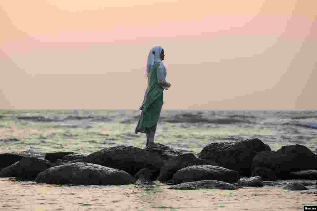 A woman watches the sun set from a beach near Cox&#39;s Bazar, Bangladesh.