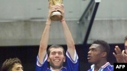 Les joueurs français Bixente Lizarazu (L) et Marcel Desailly (R) sourient alors que Zinedine Zidane détient le trophée, après la finale de la Coupe du monde 1998 entre la France et le Brésil, au Stade de France à Saint-Denis, le 12 juillet 1998.