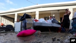 Seorang perempuan tampak memperhatikan barang-barang di rumahnya di Toa Baja, Puerto Rico, yang rusak diterjang banjir setelah badai Fiona menghantam negara tersebut pada 20 September 2022. (Foto: AP/Stephanie Rojas)