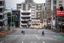 People cross nearly empty streets in the central business district of Auckland, New Zealand, Aug. 27, 2021.