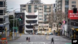 Warga menyeberangi jalanan yang sepi di tengah pembatasan wilayah di pusat bisnis Auckland, Selandia Baru, 27 Agustus 2021. (Michael Craig/NZ Herald via AP)