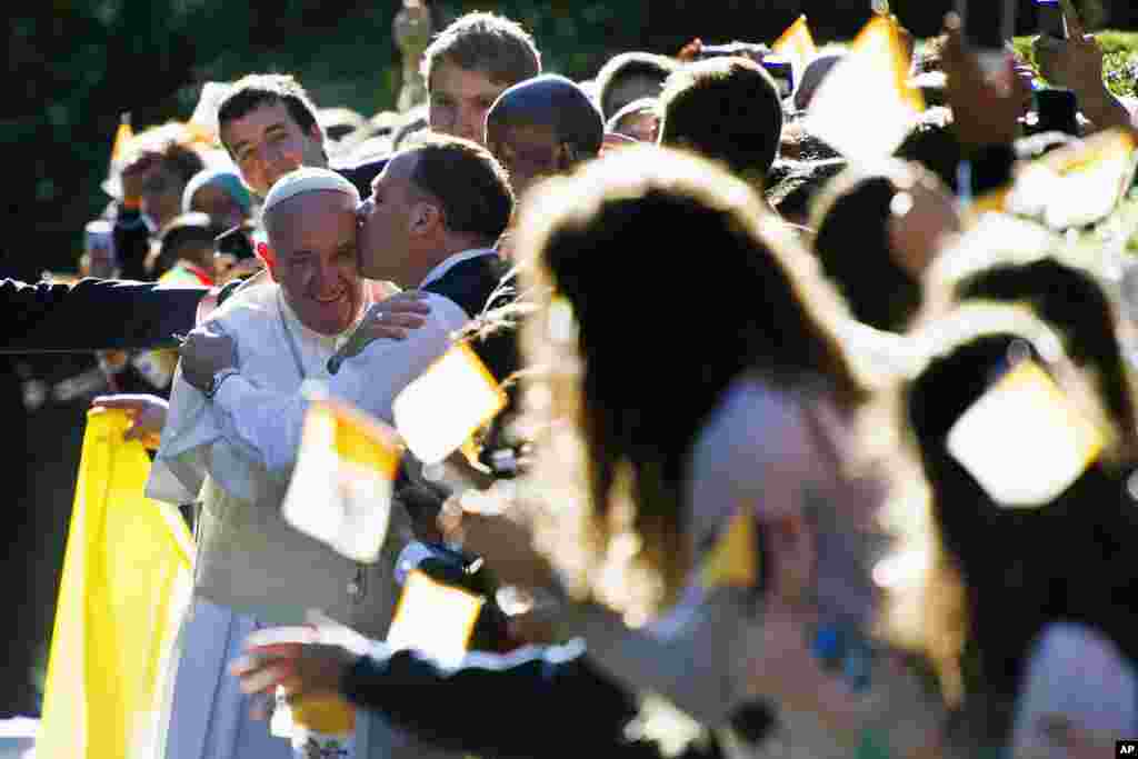 Seorang pria mencium Paus Fransiskus saat ia menyapa warga yang menyambutnya di luar Apostolic Nunciature, misi diplomatik Vatikan di Washington (23/9). (AP/Cliff Owen)