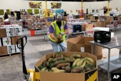 Seorang petugas meletakkan kantong ubi jalar ke dalam sebuah wadah di gudang Bank Makanan Komunitas Alameda County di Oakland, California, 5 November 2021.