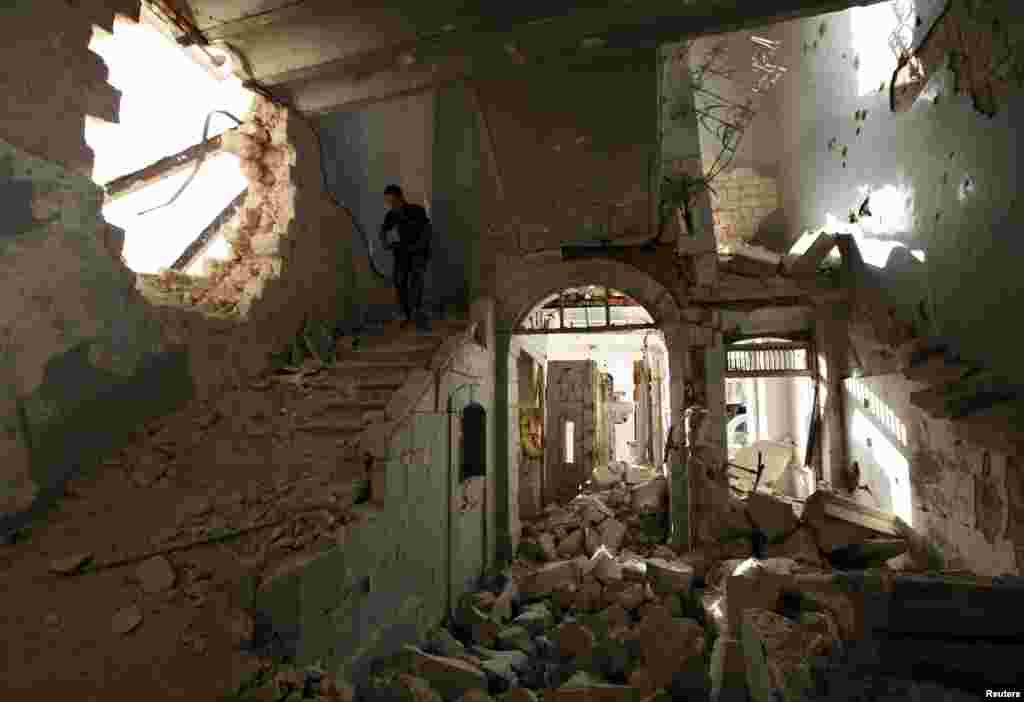 A Free Syrian Army fighter carries his weapon as he walks down the stairs of the damaged former Immigration and Passport building in Aleppo, Syria.