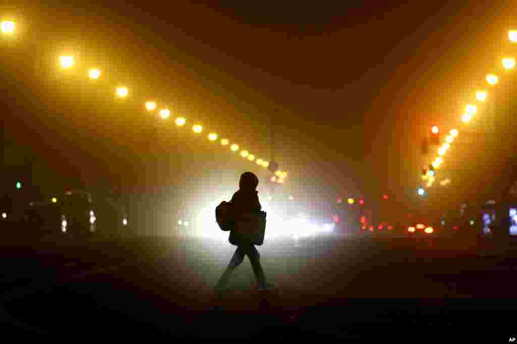 A woman crosses a road early morning in Munich. Germany has entered a harder lockdown, closing shops and schools in an effort to bring down stubbornly high new cases of the coronavirus.