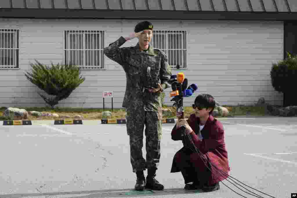 K-pop band BTS member J-Hope, center, salutes as fellow member Jin holds microphones after being discharged from a required military service outside of an army base in Wonju, South Korea.