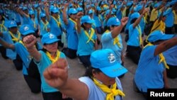 King's volunteers wearing blue caps and yellow foulards shout slogans before the start of the cleaning program at a market in Bangkok, Aug. 8, 2018.