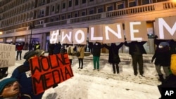 FILE - Protesters with signs reading "Free Media" gather outside Poland's state TVP building in Warsaw, Poland, Feb. 10, 2021.