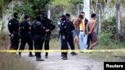 Salvadoran policemen detain two suspected gang members in a crime scene where six members of the 18th Street Gang were killed in the town of Santiago Nonualco, Dec. 20, 2014.