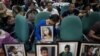 FILE - Parents of children injected with Dengvaxia vaccine carry pictures of their loved ones as they attend a senate hearing regarding the vaccine at the Senate building in Manila, Philippines, Feb. 21, 2018. 