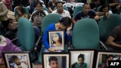 FILE - Parents of children injected with Dengvaxia vaccine carry pictures of their loved ones as they attend a senate hearing regarding the vaccine at the Senate building in Manila, Philippines, Feb. 21, 2018. 