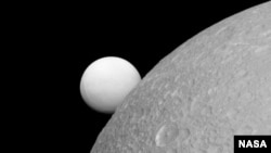 Dione with Enceladus in the background. This image was taken by the Cassini spacecraft on 8 September 2015.