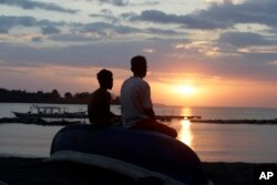 People watch the sunset in North Lombok, Indonesia, Aug. 10, 2018.