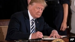 FILE - President Donald Trump signs an executive order in the East Room of the White House, in Washington, May 9, 2018.