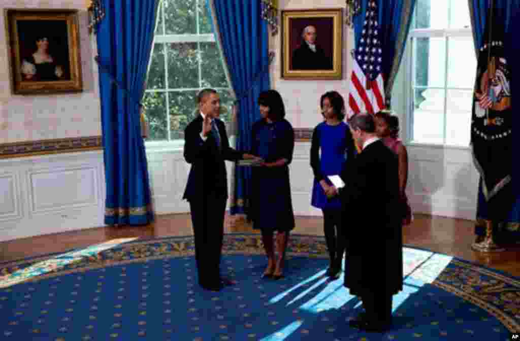 President Barack Obama takes the oath of office at the official swearing-in ceremony in the Blue Room of the White House in Washington, DC, Sunday, Jan. 20, 2013, holding the family bible is First Lady Michele Obama, administering the oath is Supreme Cour