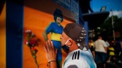 A soccer fan kisses a poster of Diego Maradona at the entrance of the Boca Juniors stadium, known as La Bombomera, in Buenos Aires, Argentina, Nov. 25, 2020.