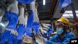 A worker inspects disposable gloves at the Top Glove factory in Shah Alam on the outskirts of Kuala Lumpur, Malaysia, Aug. 26, 2020.