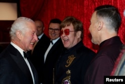 Raja Inggris Charles bertemu dengan Elton John dan David Furnish saat tiba di Royal Variety Performance di Royal Albert Hall, London, Inggris, 22 November 2024. (Foto: Toby Melville/Pool/REUTERS)