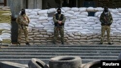 Armed men, who are wearing black and orange ribbons of St. George - a symbol widely associated with pro-Russian protests in Ukraine, stand guard in front of barricades outside the mayor's office in Slovyansk, April 18, 2014. 