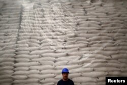 A worker poses for a photo in front of sacks filled with sugar at Emiliano Zapata sugar mill in Zacatepec de Hidalgo, in Morelos state, Mexico, March 7, 2015.